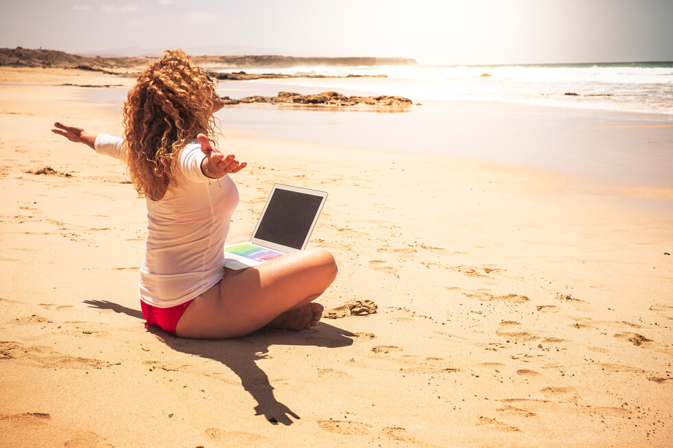 Woman Using Laptop on the Beach
